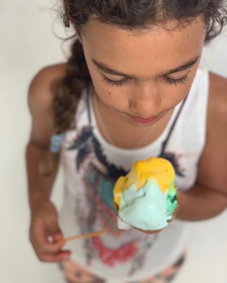 Matthew McConaughy and Camila Alves's cute daughter looks down at a yellow and blue ice cream.